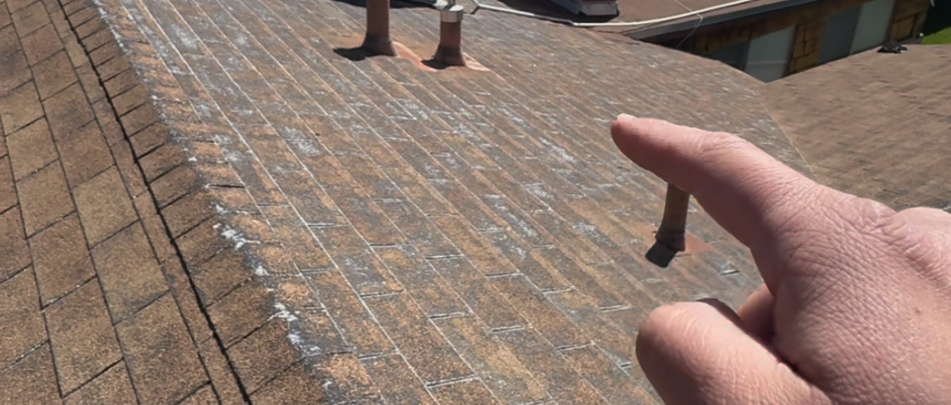 Home inspector pointing at worn asphalt shingle roof with vent pipes during a spring roof inspection in Murrieta, CA.