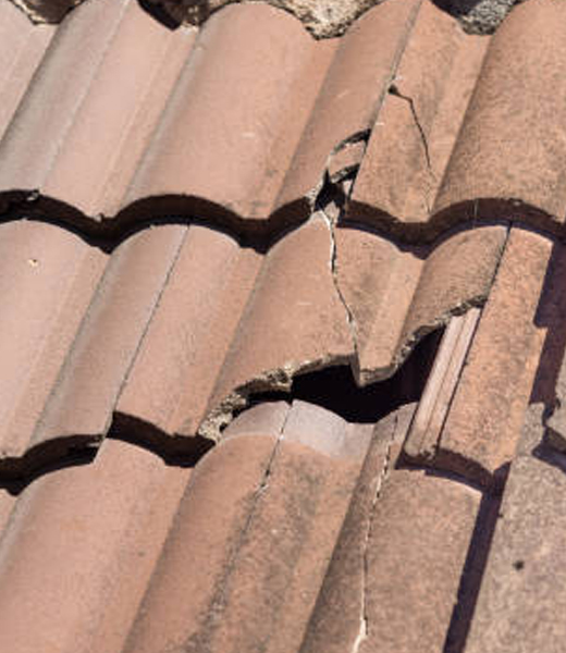 Cracked and broken clay roof tiles requiring repair on residential home