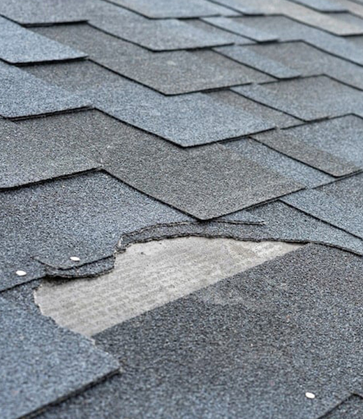 Damaged asphalt shingle roof showing missing and torn shingles in need of repair